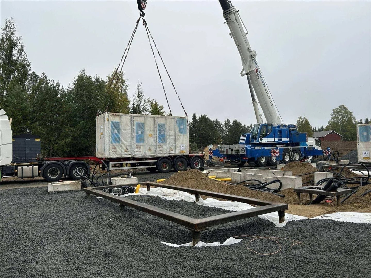 Batterijcontainer wordt met een kraan op een stalen frame op schroefpalen geplaatst
