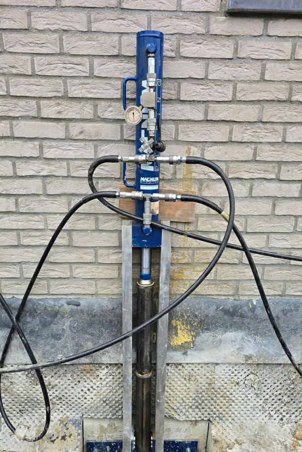 Magnum-vijzel met manometer op een stalen console onder de fundering