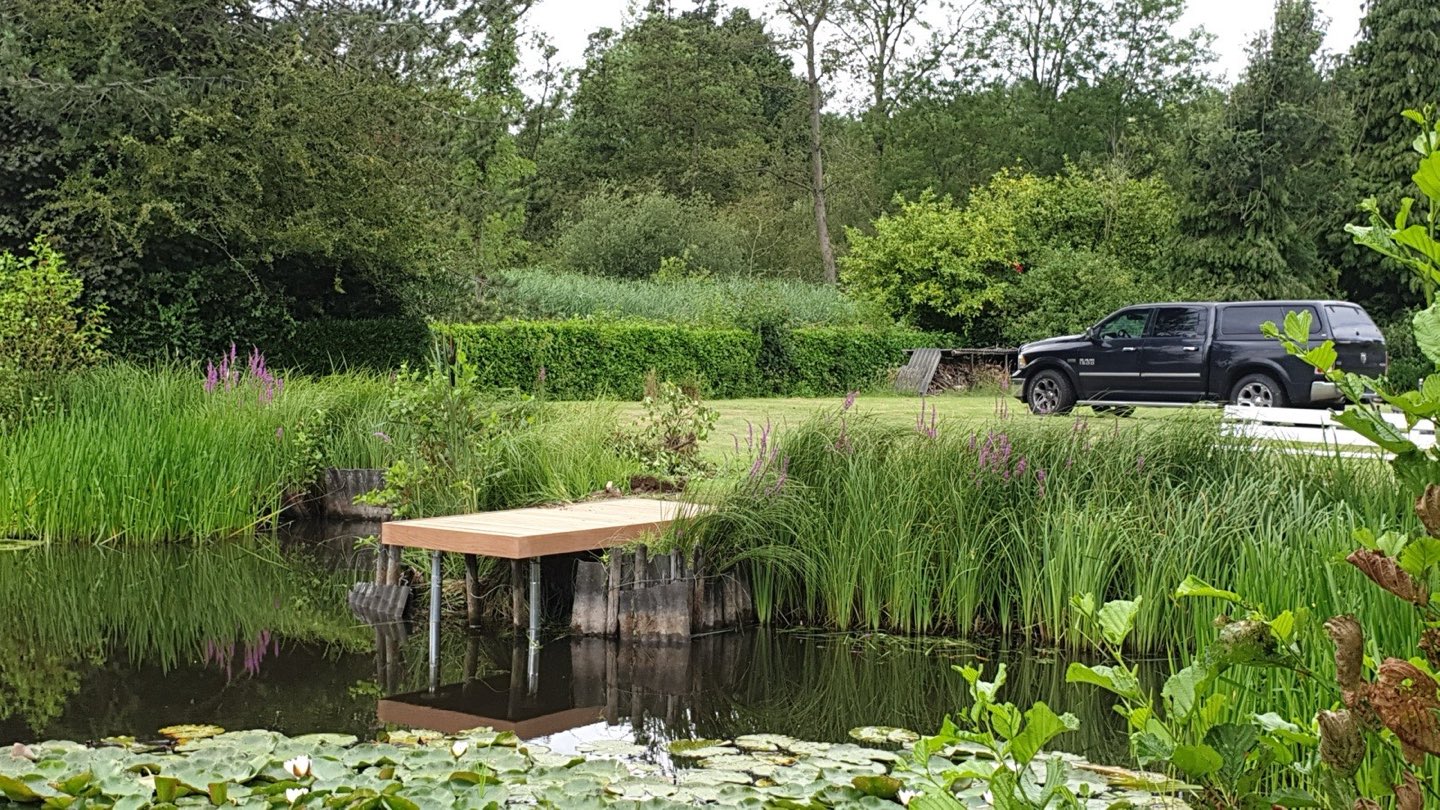 Afgewerkte houten steiger boven het water van een tuinvijver