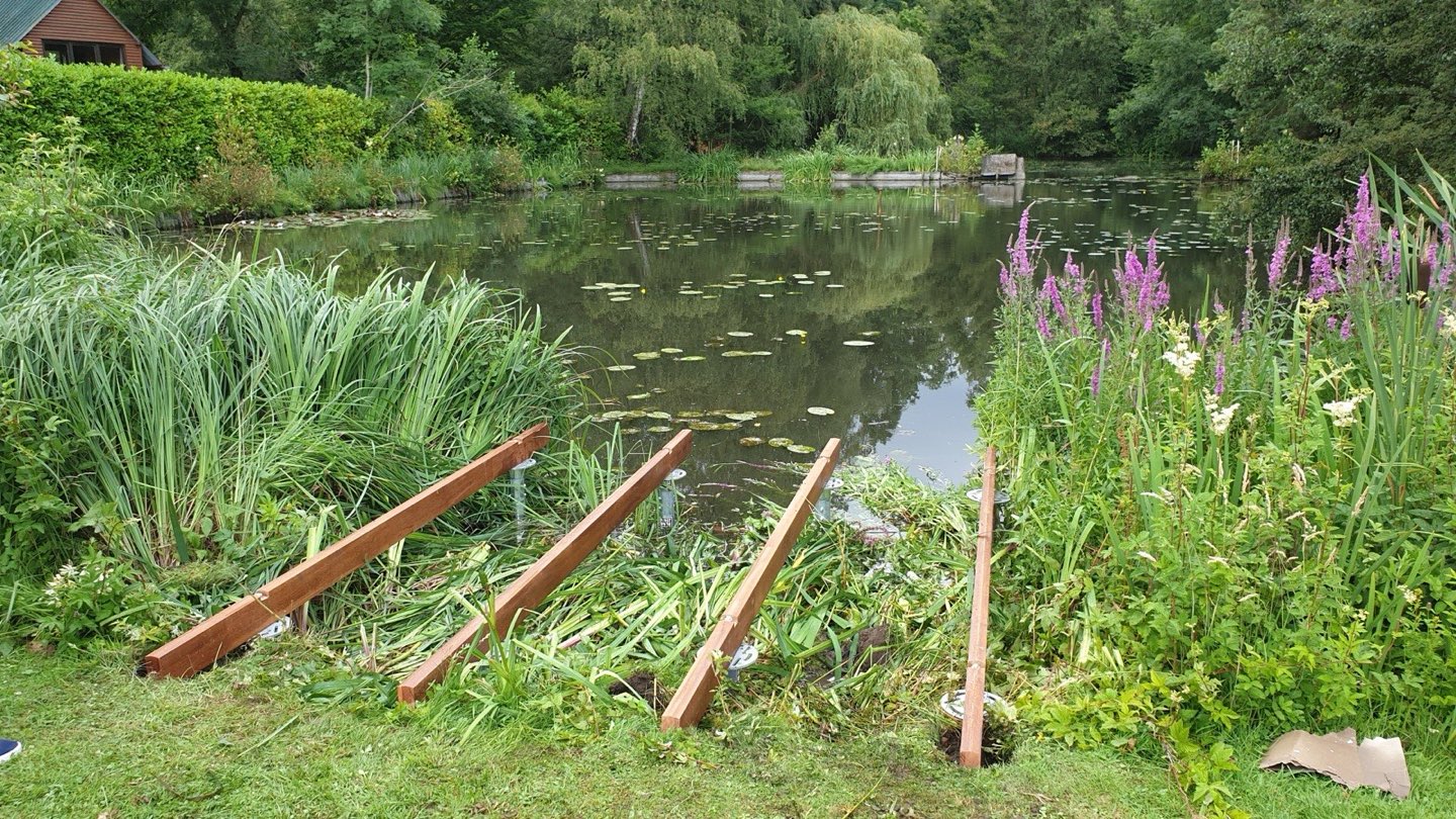 Schroefpalen klaar voor plaatsing aan de rand van een tuinvijver