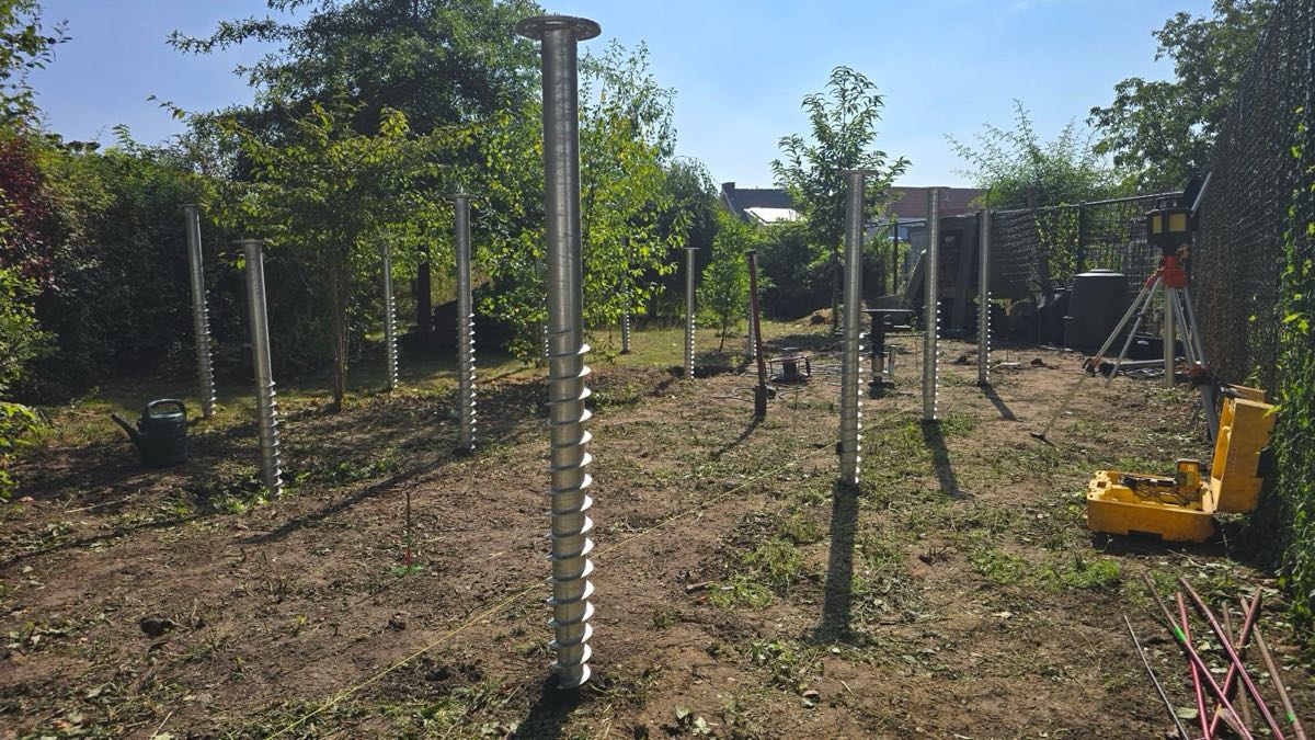 Lange schroefpalen in een tuin met een laser op statief