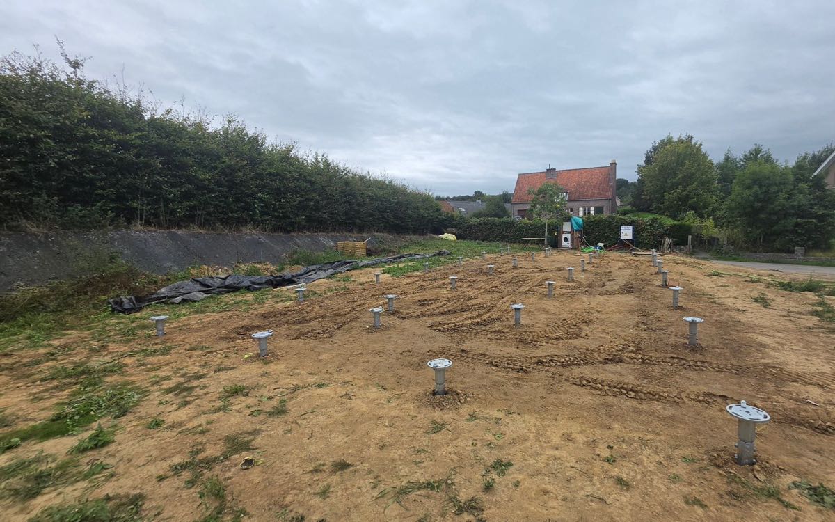 Geplaatste schroefpalen met paalkoppen op een bouwgrond